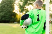 Junge steht im Tor und trägt ein grünes Fußball-Trikot